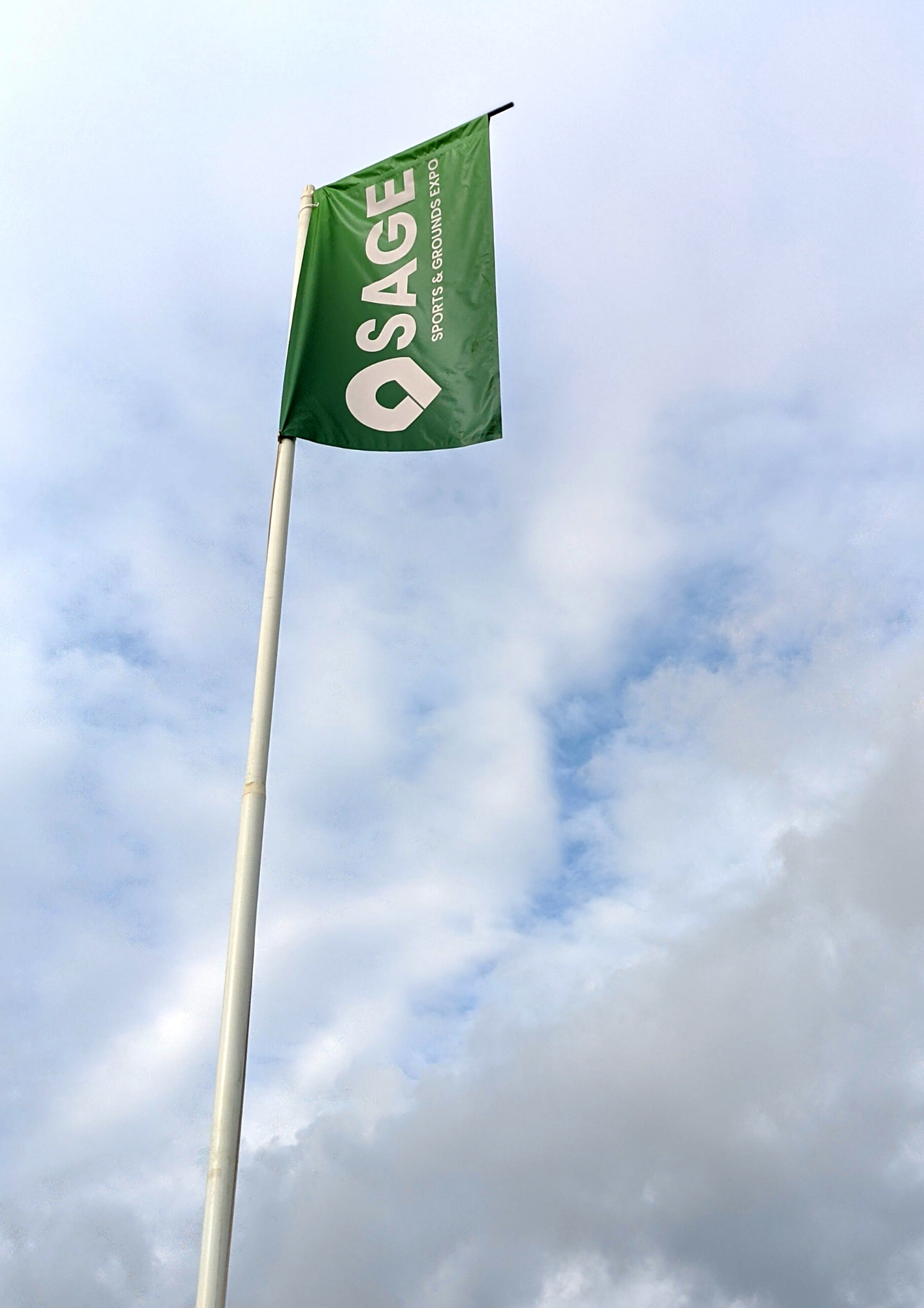 Green flag with white writing saying SAGE on a white pole